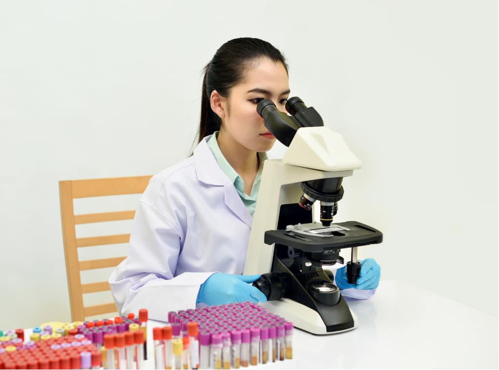 A medical laboratory professional doing IVF in Vietnam by conducting diagnostic tests with a microscope and blood samples.