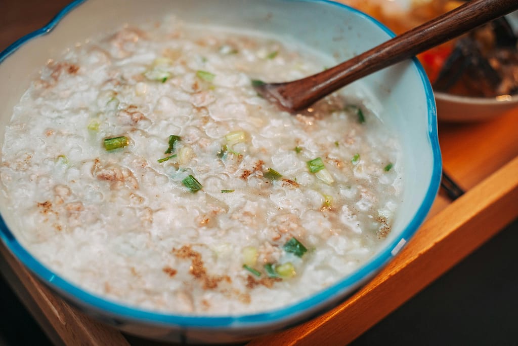 Warm and comforting homemade rice porridge with scallions in a ceramic bowl, perfect for breakfast.