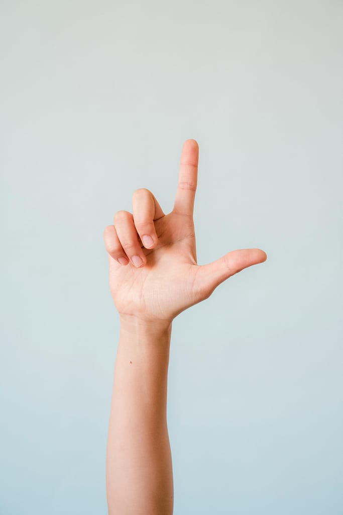 Close-up of a hand gesturing in sign language against a light background.